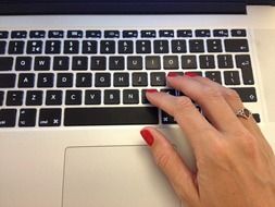 hand with red manicure on a laptop keyboard