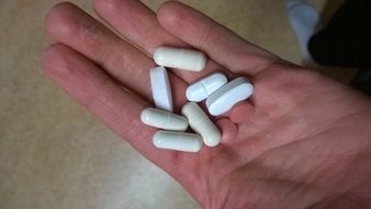 white and pink pills on hand