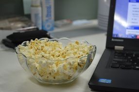 popcorn in bowl at computer on desk