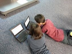 children with laptops on the floor in the room