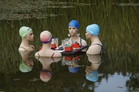 Mannequins in swimming caps in the lake