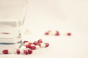 Capsules with medicine near the glass with water