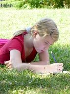 girl writes poetry while lying on the grass