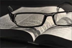 opened book and glasses black and white view