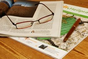 glasses, magazines and a pen on the table