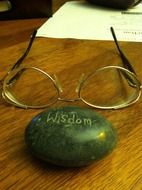 stone with the inscription wisdom and glasses on the table