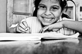 happy nice asian child girl with open notebook at table, black and white