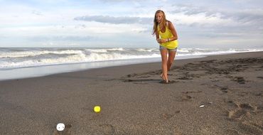 girl in yellow jersey plays on the beach