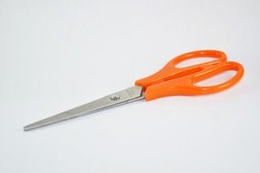 scissors with orange handles on a light background