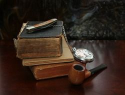 still life with old pile of books, watch and smoking pipe