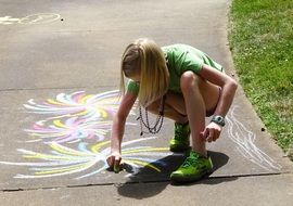 girl draws with chalk on the pavement