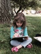 little girl doing homework under a tree