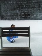 the girl is at the blackboard behind the chair
