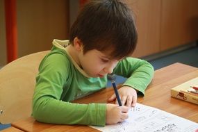 child boy writing at desk, pupil