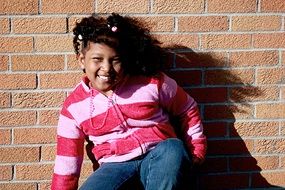 girl in a striped sweater on a brick wall background