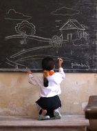 girl draws a house and a tree on the board