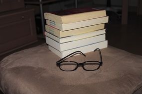 stack of books and black reading glasses