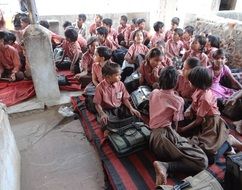 school children sitting on floor, india, abhaneri