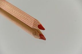 wooden pencil with red core on the background of reflective surface