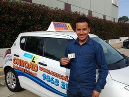 happy man with driver's license at onroad driving school car