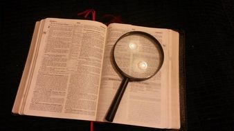 opened bible and magnifying glass