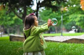 asian little girl with soap bubbles in the park