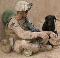 dog is sittoing next to soldier