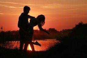 loving couple near the water on the sunset background