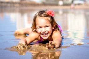 happy girl lies on wet sand at the beach