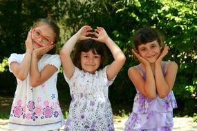 happy child girls in dresses folded hands in different poses