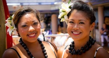 portrait of two smiling polynesian women with flowers in hairs