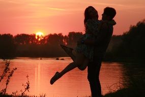 loving boy holding girl on the hands on the sunset background