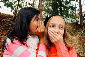 girls whispering and smiling in park