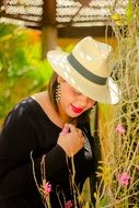 woman in a hat at the rose Bush