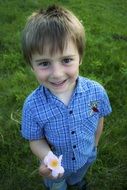 boy with a flower in his hand on green grass