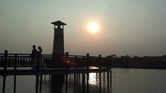 silhouette of couple on pier at sunset