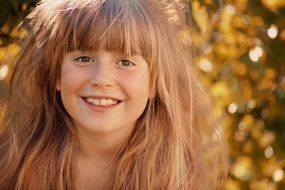 Blonde long haired smiling girl at colorful autumn leaves