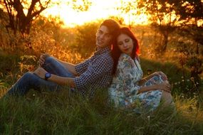 love couple on green grass against the setting sun