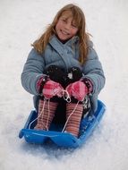 girl in a winter jacket on a blue sled