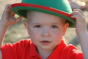 child boy in red shirt and green hat