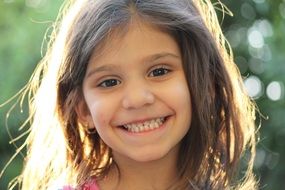 smilig long haired child girl in back light, portrait