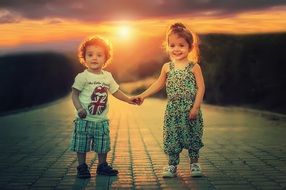 small children holding hands at sunset