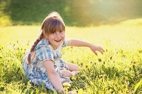 blond girl sitting on the meadow