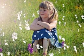 cute blond girl sitting on the meadow