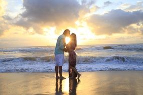 kiss of a couple in love near the sea at sunset