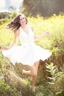 happy girl in a white dress runs across the meadow