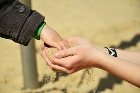 sand in the hands of an adult and a child