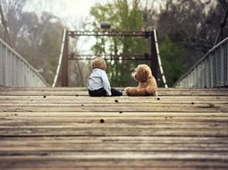 Baby boy and teddy bear on a bridge