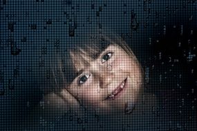 The child's face through the window glass and raindrops