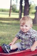 happy baby on a red bedspread in the park